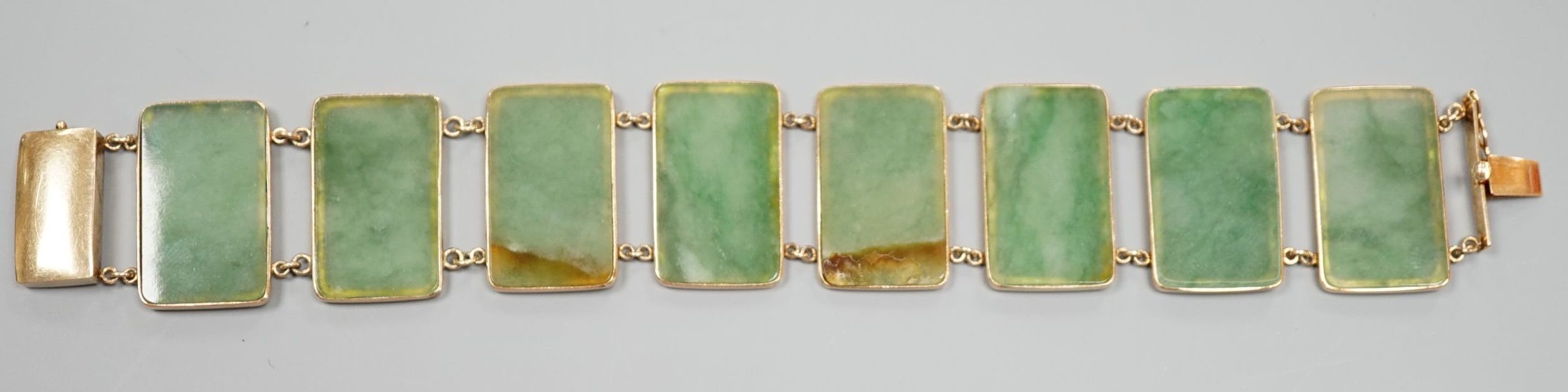 A 585 yellow metal and jade bracelet, set with eight rectangular panels, 18cm, gross weight 26.5 grams.